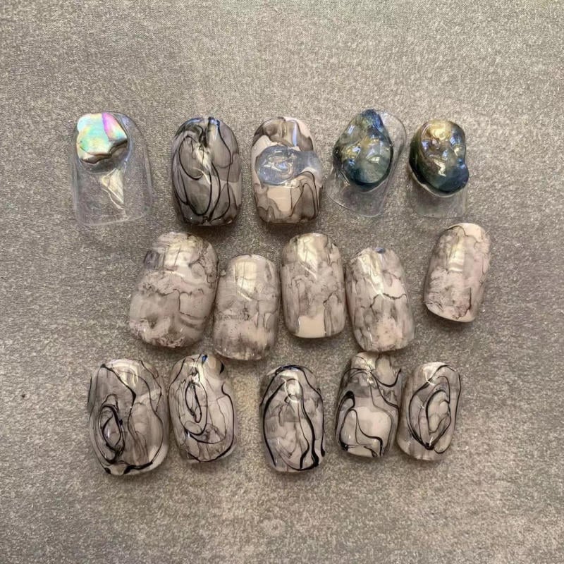 nail-van-da-dep__44__932d722195c6413bb13d87927033a0ad Bộ móng giả nghệ thuật với họa tiết đá cẩm thạch trắng đen, một số móng có điểm nhấn màu sắc lấp lánh.