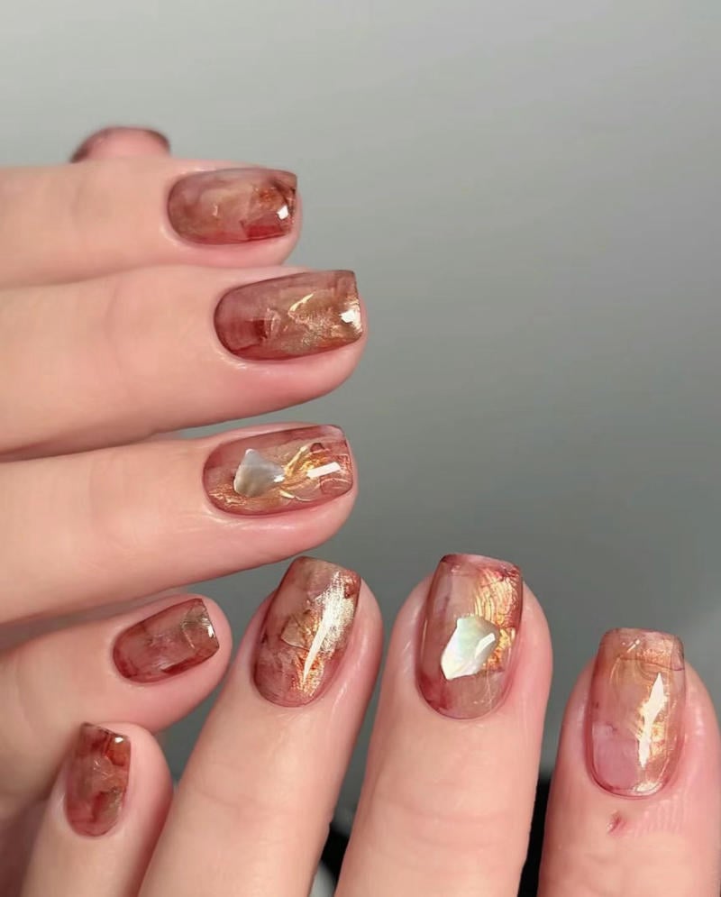nail-van-da-dep__59__b94d7280b43b4f60bf02c641958be5cf Móng tay được trang trí với lớp sơn màu nâu đỏ và ánh kim, tạo hiệu ứng vân đá cẩm thạch óng ánh.