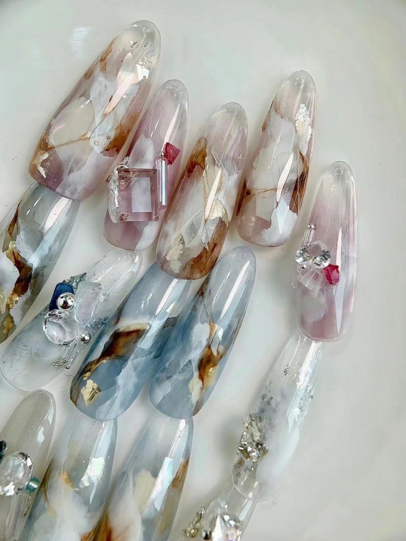 nail-van-da-dep__71__48f66423a0c14a66b755681a0fd6f226 Bộ móng tay giả dài với nhiều màu sắc và họa tiết đá cẩm thạch, trang trí bằng đá quý nhỏ.