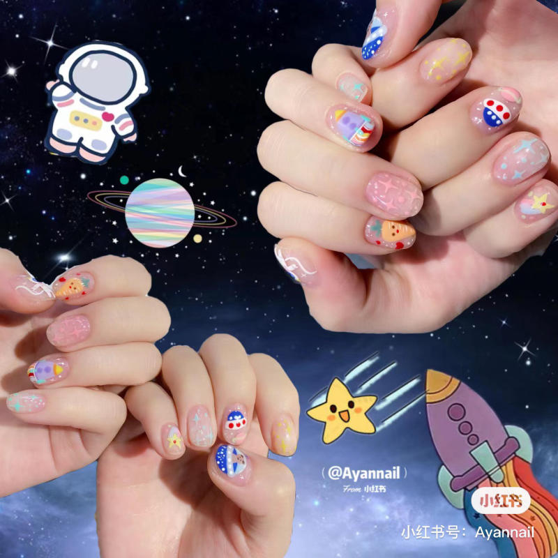 Mẫu nail chủ đề vũ trụ với hình ảnh phi hành gia, hành tinh và ngôi sao trên nền không gian.