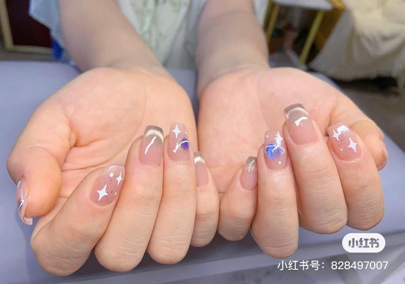 Đôi tay với móng tay được trang trí họa tiết ngôi sao và hình vẽ màu sắc nổi bật.