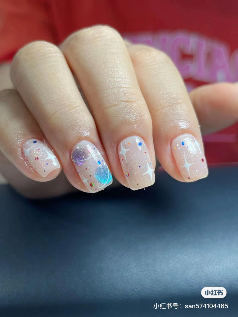 Bàn tay với móng tay được sơn màu sáng, trang trí hoa văn và kim tuyến lấp lánh.