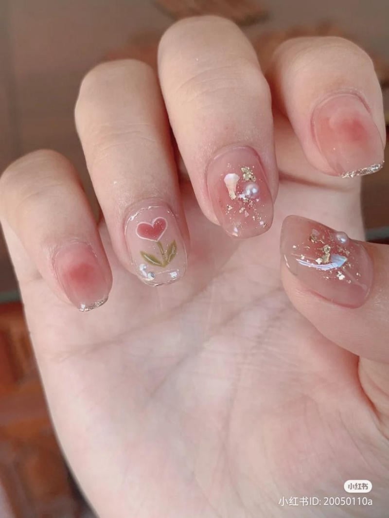 Bàn tay với móng tay được trang trí bằng hoa văn và họa tiết nhỏ, có màu sắc tinh tế và lấp lánh.