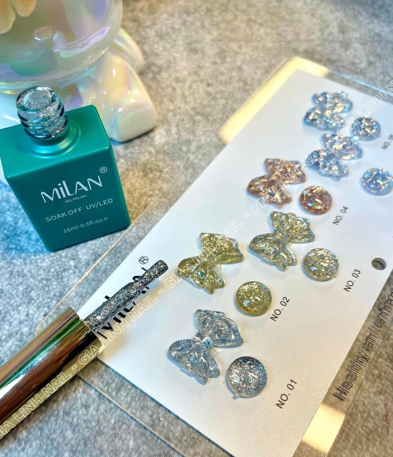 Lọ sơn gel màu xanh bên cạnh bảng mẫu đá trang trí móng tay hình nơ và tròn lấp lánh.