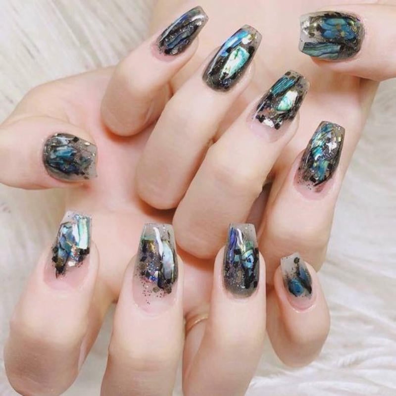 Bàn tay với móng tay được trang trí nghệ thuật, màu sắc lấp lánh và hoa văn tinh tế.