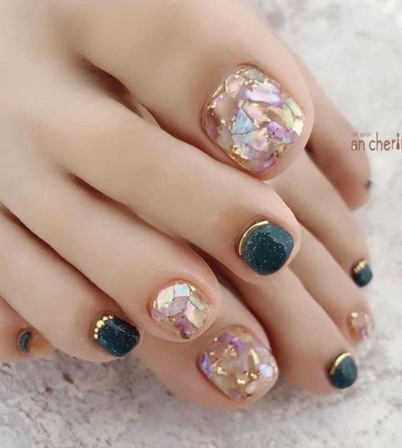 Chân với bộ móng chân được trang trí nghệ thuật, màu sắc đa dạng và họa tiết lấp lánh hấp dẫn.