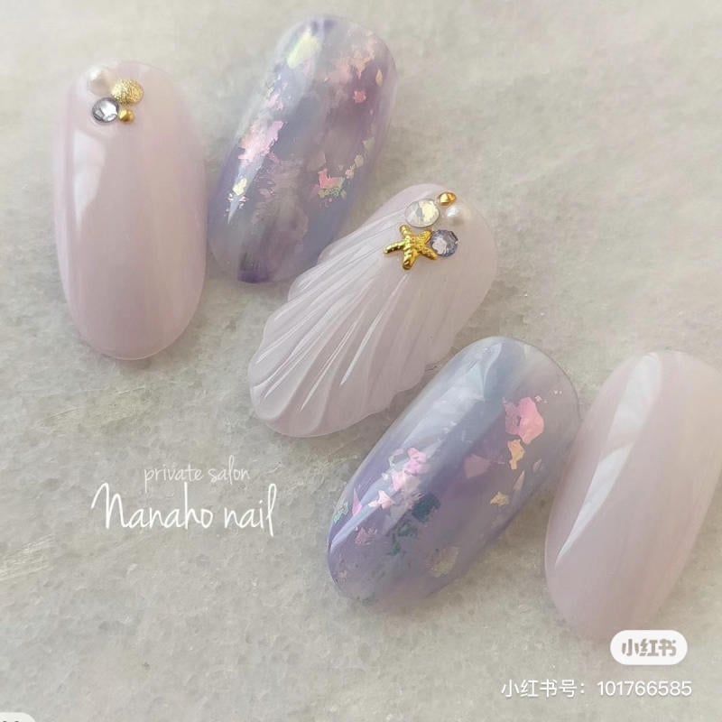 Năm móng tay giả với thiết kế màu pastel, trang trí đá và họa tiết ánh kim lấp lánh.