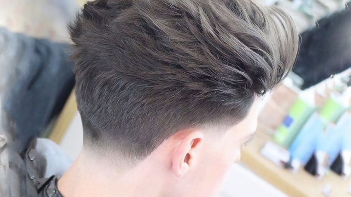 nau-xam-5 Mái tóc được cắt kiểu undercut, phần trên dài và tạo kiểu, nền mờ phía sau là một tiệm cắt tóc.