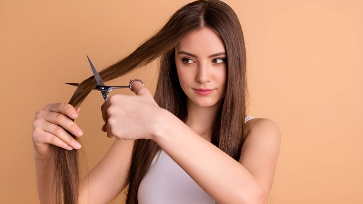 Người phụ nữ cắt tóc dài bằng kéo, nền màu cam nhạt.