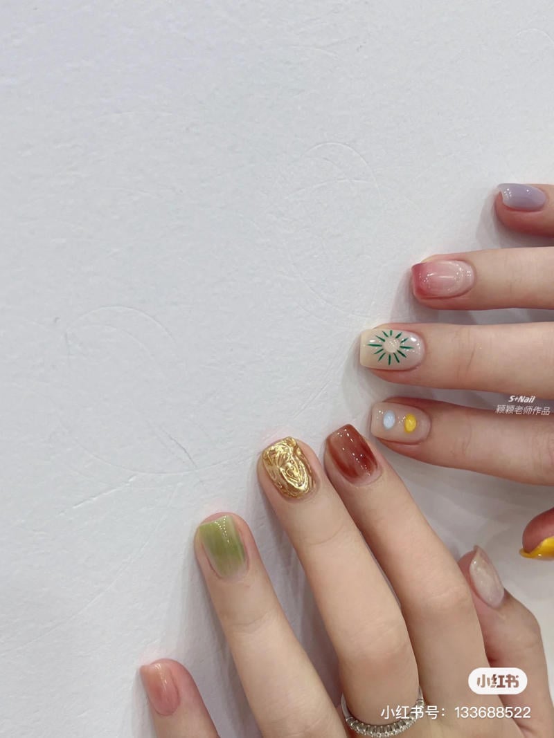 B&agrave;n tay với m&oacute;ng tay được trang tr&iacute; bằng nhiều m&agrave;u sắc v&agrave; họa tiết kh&aacute;c nhau tr&ecirc;n nền trắng.