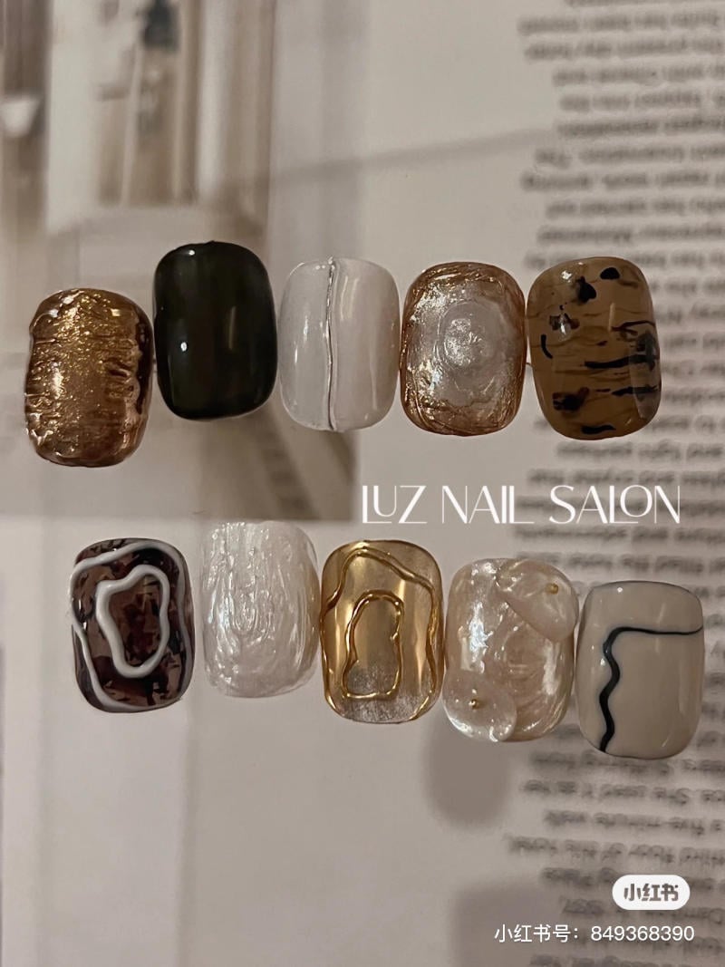 Bộ m&oacute;ng tay giả với nhiều m&agrave;u sắc v&agrave; hoa văn kh&aacute;c nhau, bao gồm m&agrave;u v&agrave;ng, đen, trắng v&agrave; n&acirc;u.