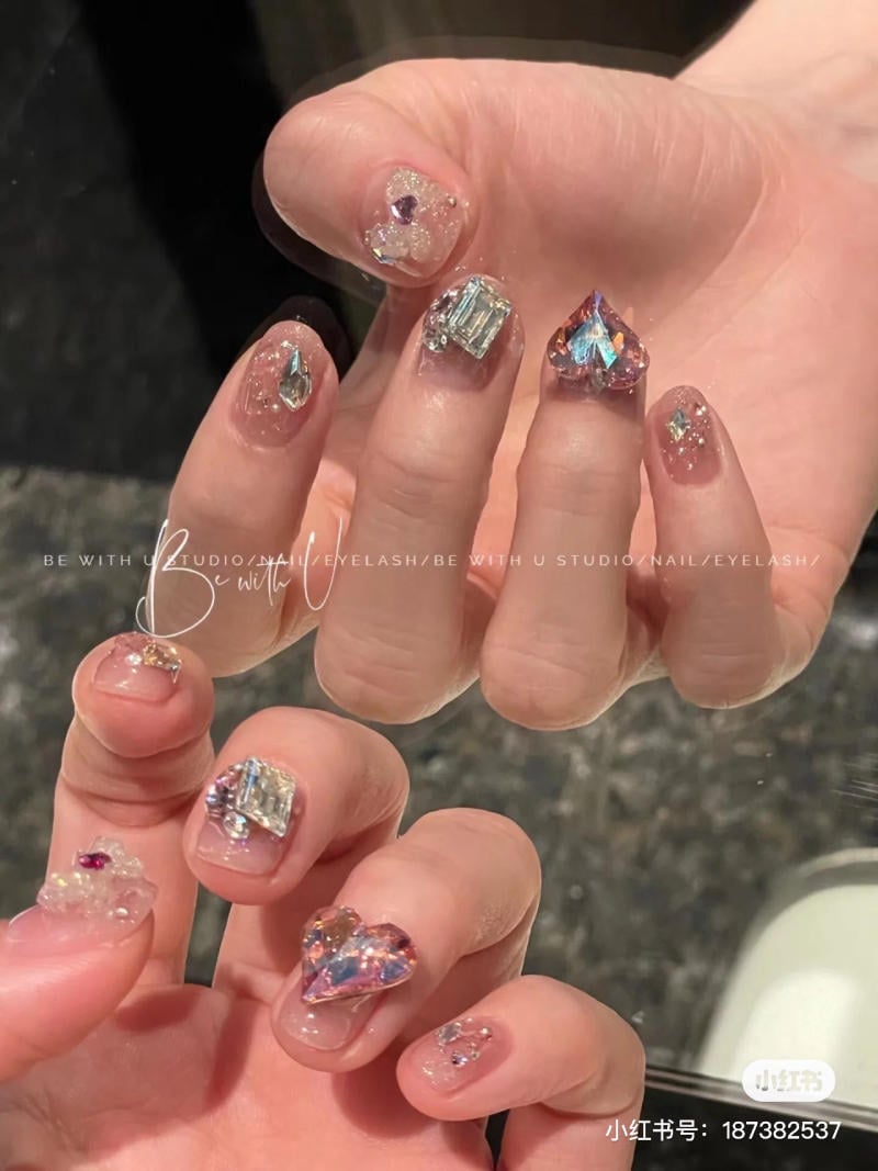 B&agrave;n tay với m&oacute;ng tay đ&iacute;nh đ&aacute; lấp l&aacute;nh, thiết kế đa dạng tr&ecirc;n nền m&oacute;ng trong suốt.