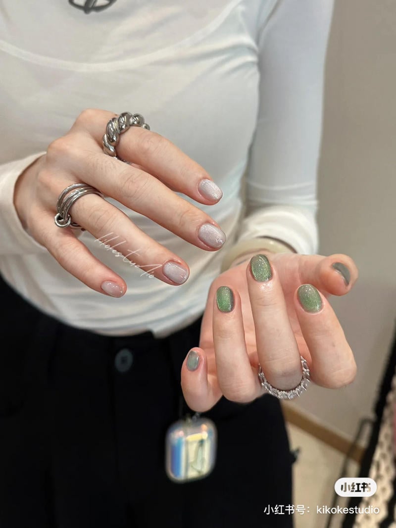 Đ&ocirc;i tay đeo nhẫn bạc, m&oacute;ng tay sơn m&agrave;u hồng nhạt v&agrave; xanh l&aacute;, &aacute;o trắng v&agrave; quần đen.