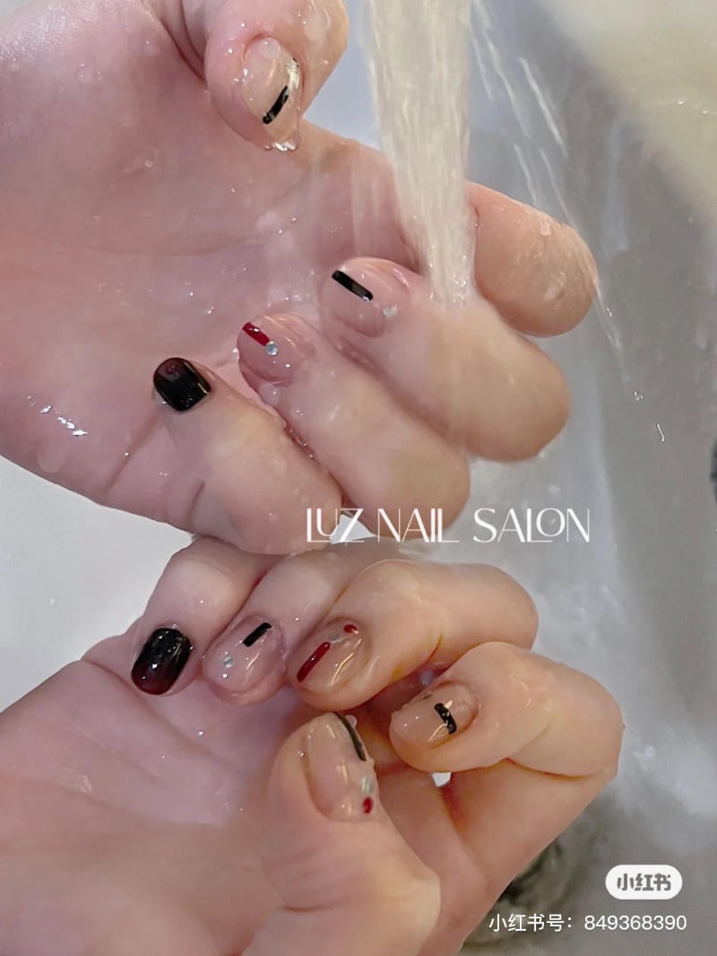 Hai b&agrave;n tay với m&oacute;ng tay được sơn m&agrave;u sắc đa dạng đang rửa dưới v&ograve;i nước.