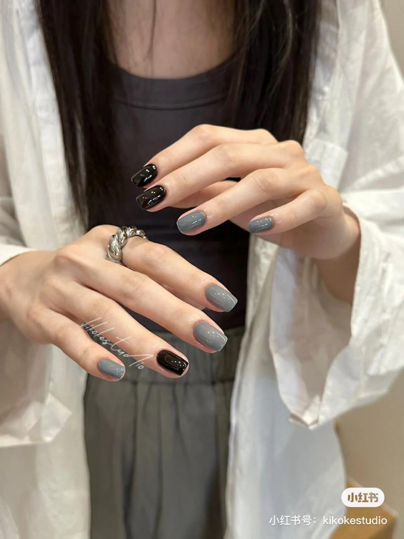 B&agrave;n tay với m&oacute;ng tay sơn m&agrave;u x&aacute;m v&agrave; đen, đeo nhẫn bạc, người mặc &aacute;o trắng v&agrave; &aacute;o tối m&agrave;u.