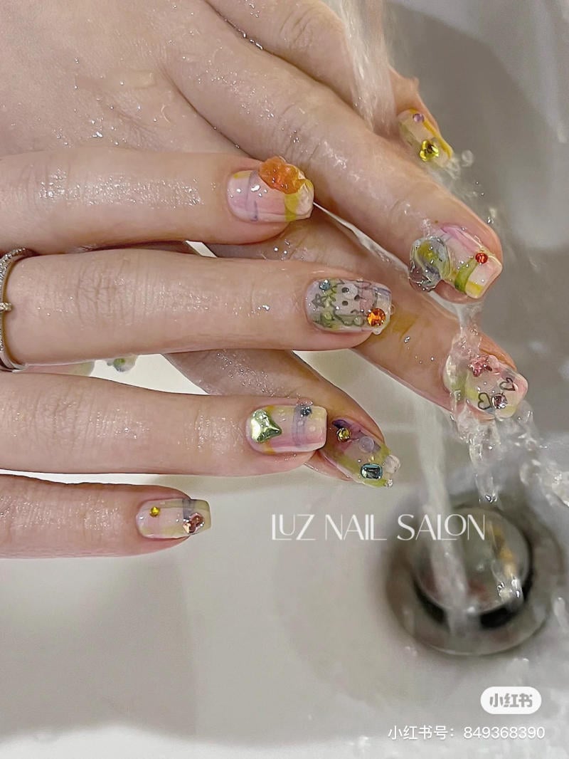 B&agrave;n tay với m&oacute;ng tay được trang tr&iacute; họa tiết v&agrave; m&agrave;u sắc đa dạng, đang rửa dưới v&ograve;i nước chảy.