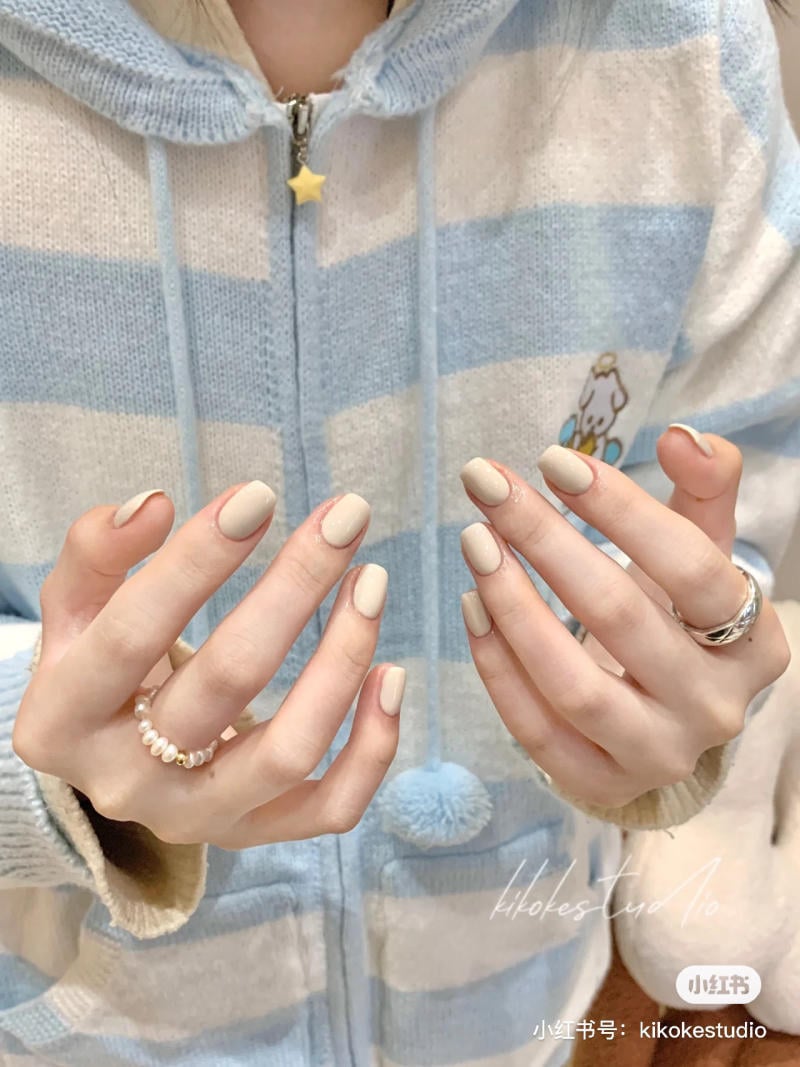 Người mặc &aacute;o len sọc xanh trắng, với m&oacute;ng tay sơn m&agrave;u nude v&agrave; đeo nhẫn bạc c&ugrave;ng v&ograve;ng ngọc trai.