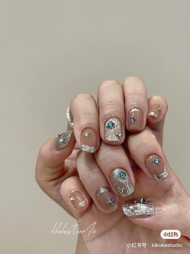 B&agrave;n tay với m&oacute;ng tay được trang tr&iacute; bằng sơn kim loại v&agrave; đ&iacute;nh đ&aacute; m&agrave;u sắc.