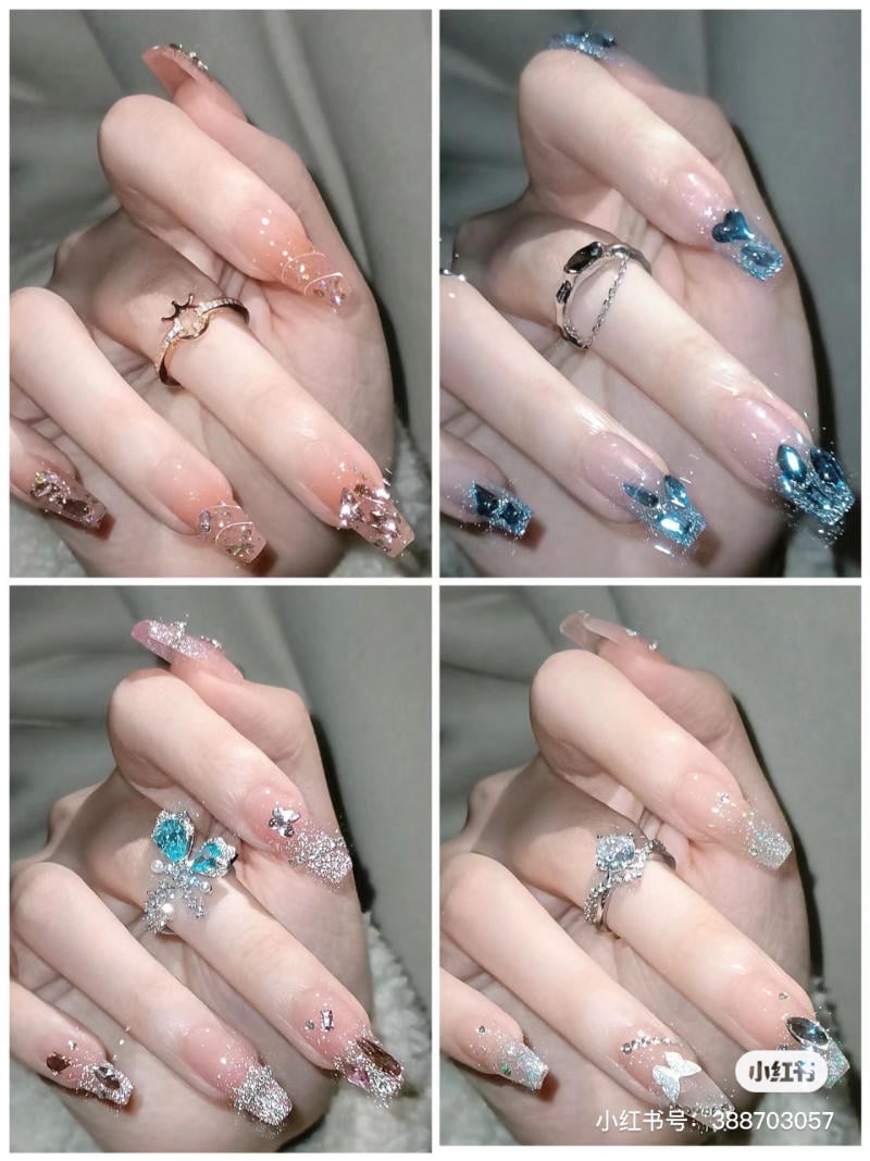 Bàn tay với móng tay được trang trí đa dạng, đeo nhẫn bạc và vàng, nền màu xám.