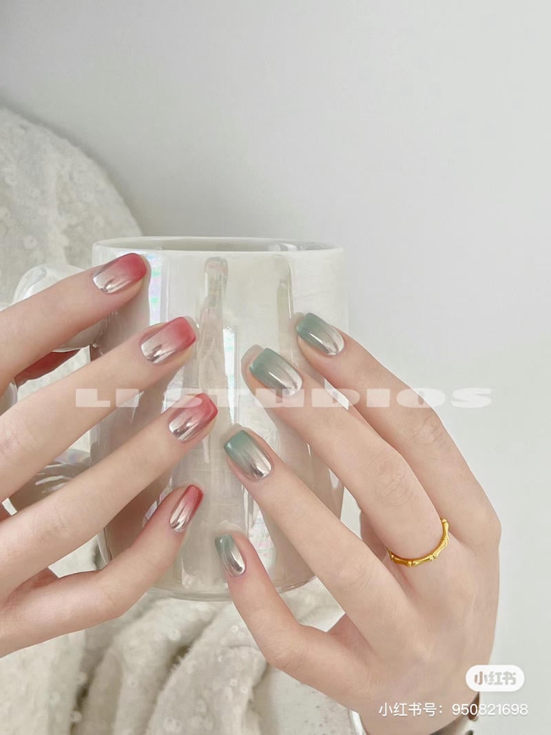 Bàn tay với móng tay sơn màu ombre cầm một chiếc cốc sứ trắng, có đeo nhẫn vàng trên ngón tay.