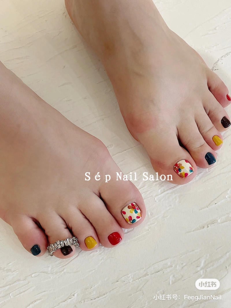 Bàn chân với móng được sơn nhiều màu sắc và hoa văn. Một chiếc nhẫn đeo trên ngón chân.