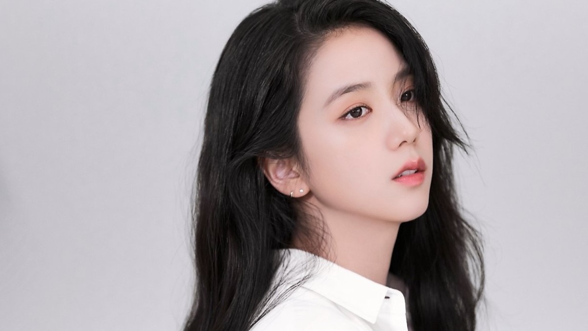 toc-jisoo-9 Người phụ nữ với mái tóc đen dài, mặc áo sơ mi trắng, nhìn nghiêng trên nền xám.