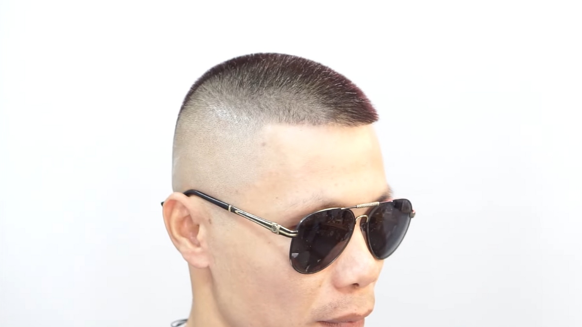 Người đeo kính râm, tóc cắt ngắn kiểu crew cut, nền trắng đơn giản.
