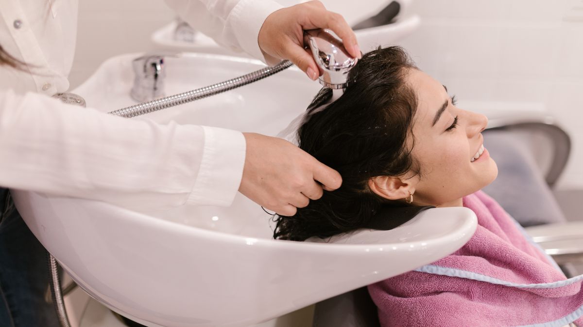 Người phụ nữ đang được gội đầu tại salon, nằm thư giãn trong bồn rửa tóc trắng.