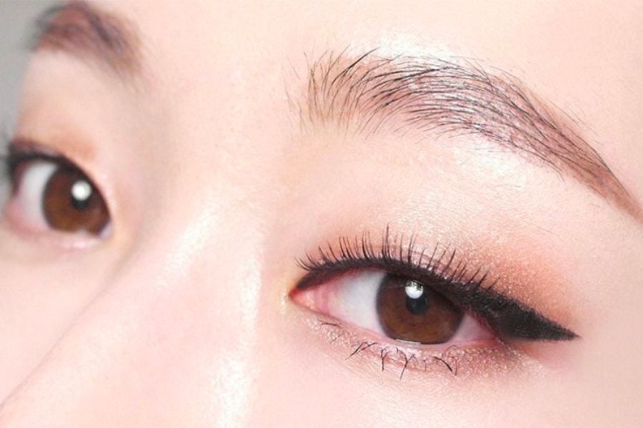 Cận cảnh đôi mắt trang điểm với eyeliner đen và lông mày gọn gàng.