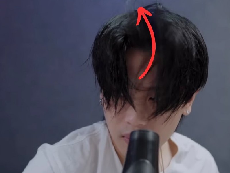 Người có mái tóc đen dài che mặt, với một mũi tên màu đỏ chỉ lên trên từ đỉnh đầu.