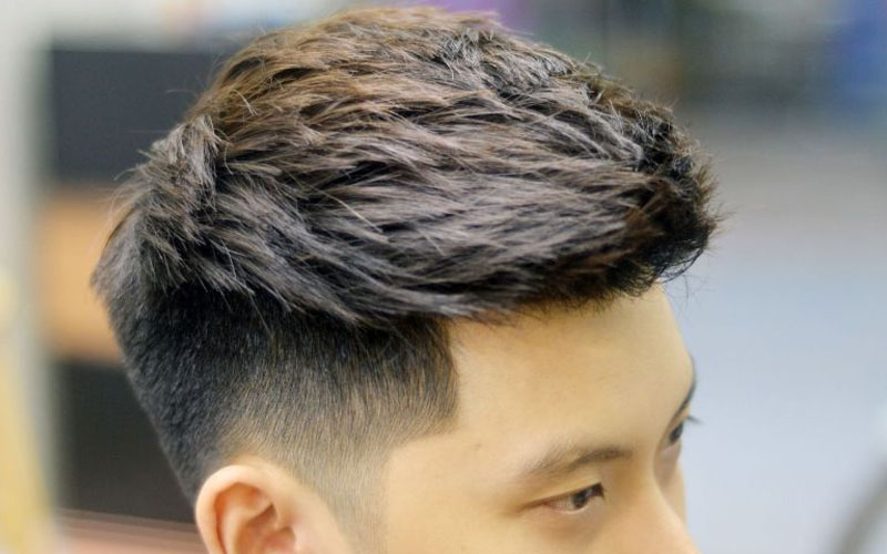 Top 30 Kiểu Tóc Nam Đẹp & Cá Tính 2025: Xu Hướng Nổi Bật 1 Người đang có kiểu tóc ngắn gọn gàng, phía trên để dài hơn, tạo kiểu gọn gàng và hiện đại trong không gian trong nhà.