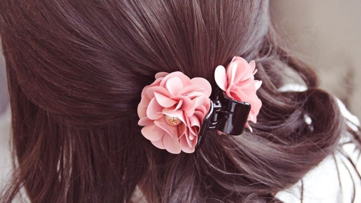 Tóc dài được buộc gọn bằng kẹp hoa màu hồng, tạo điểm nhấn nữ tính và trang nhã.