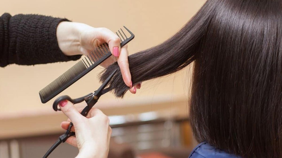 Người đang cắt tóc bằng kéo và lược, với mái tóc dài màu đen.