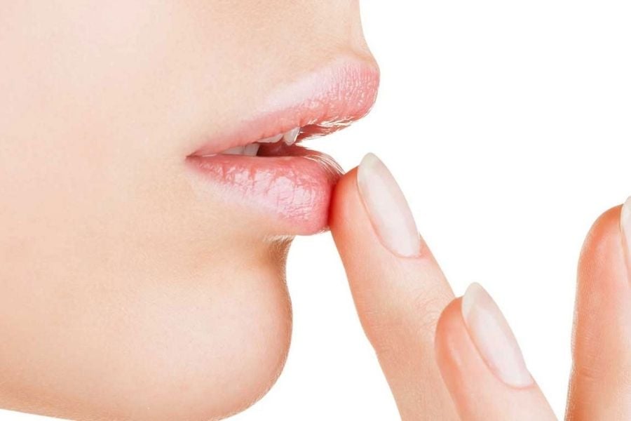 Đôi môi cận cảnh với ngón tay chạm nhẹ, nền trắng.