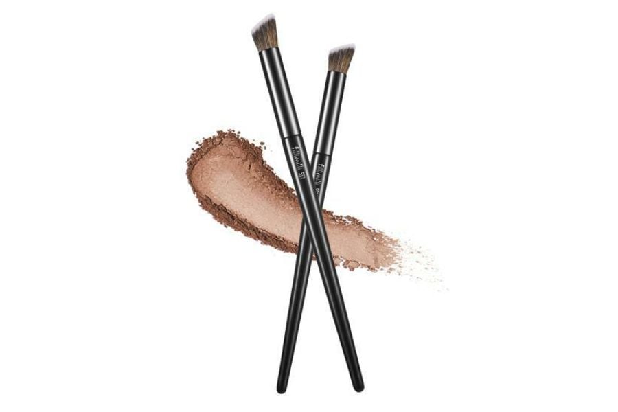 Hai cọ trang điểm giao nhau trên nền trắng, kèm vệt phấn màu nâu nhạt phía sau.