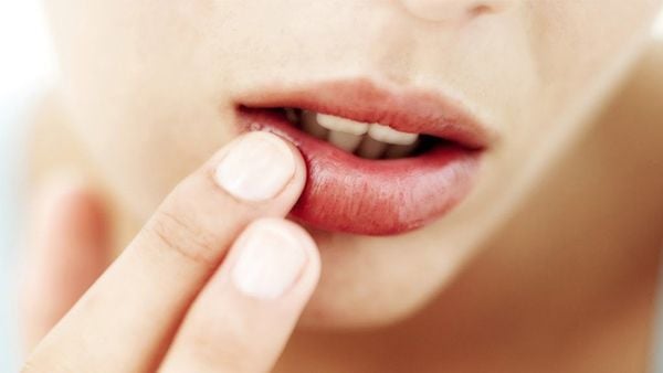 Người chạm v&agrave;o m&ocirc;i dưới của m&igrave;nh bằng ng&oacute;n tay, cận cảnh khu&ocirc;n mặt v&agrave; đ&ocirc;i m&ocirc;i.