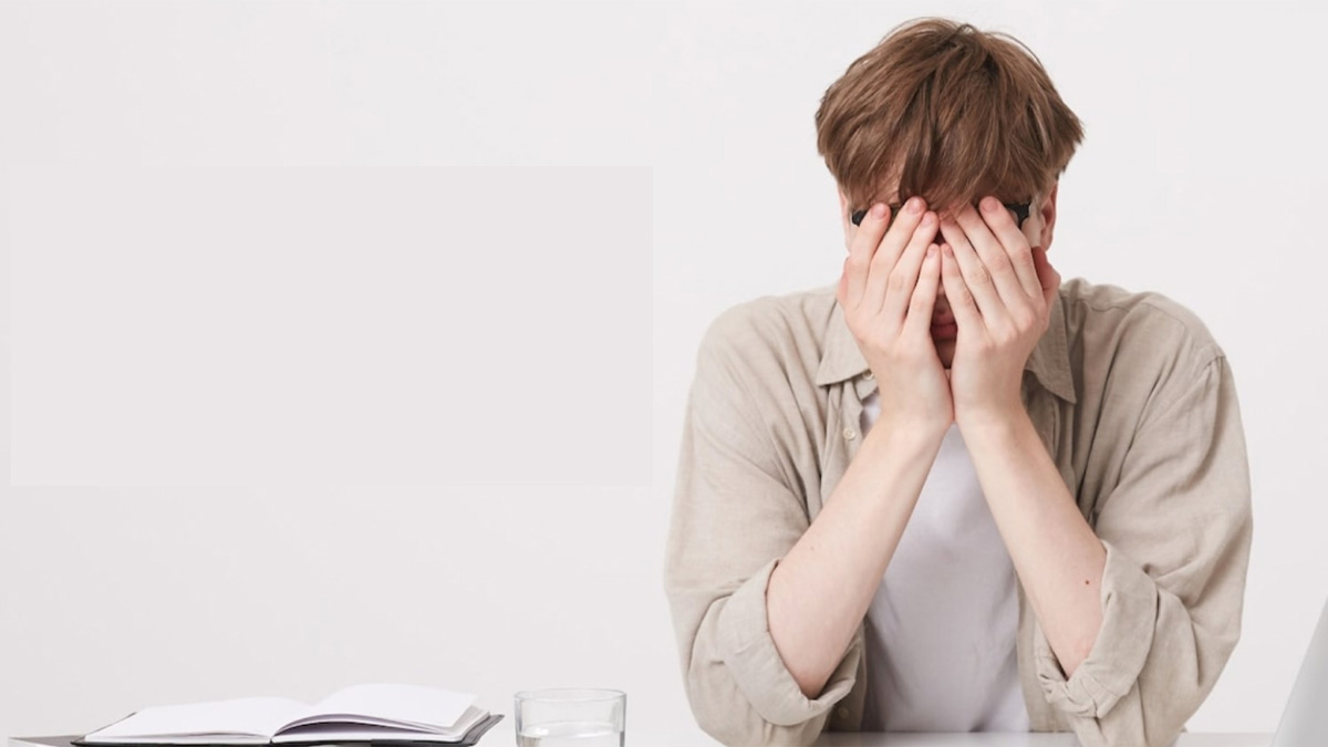 dau-nam-co-nen-cat-toc-10 Người ngồi bàn, tay che mặt, trước mặt có sổ ghi chép và ly nước.