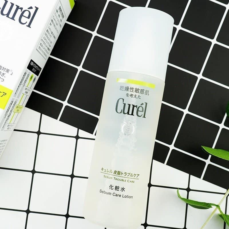Chai lotion Curel đặt tr&ecirc;n nền gạch đen trắng, b&ecirc;n cạnh l&agrave; hộp đựng c&ugrave;ng thương hiệu.
