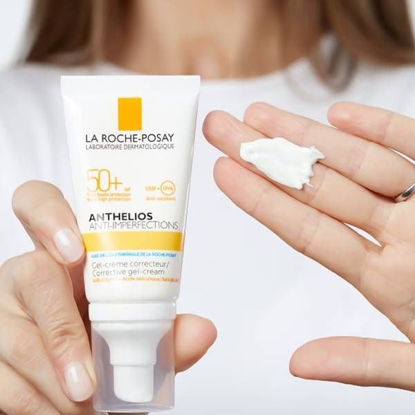 Người cầm tuýp kem chống nắng La Roche-Posay và một ít kem trên ngón tay.