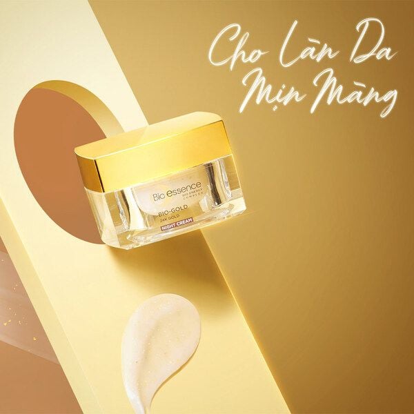 kem_duong_ban_dem_bio-essence_bio-gold_night_cream_40g_cb7f5bc6c4644b32b7af7eeb5b2c0e2a_grande Hũ kem dưỡng da với nắp vàng, nền vàng, có chữ "Cho Làn Da Mịn Màng" và một vệt kem trắng bên dưới.