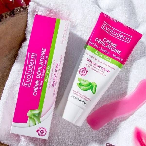 kem_tay_long_cua_phap_evoluderm_05f1e8f9ccd9492f935220b938a490e5_grande Tuýp và hộp kem tẩy lông Evoluderm Aloe Vera màu hồng trắng đặt trên khăn trắng.