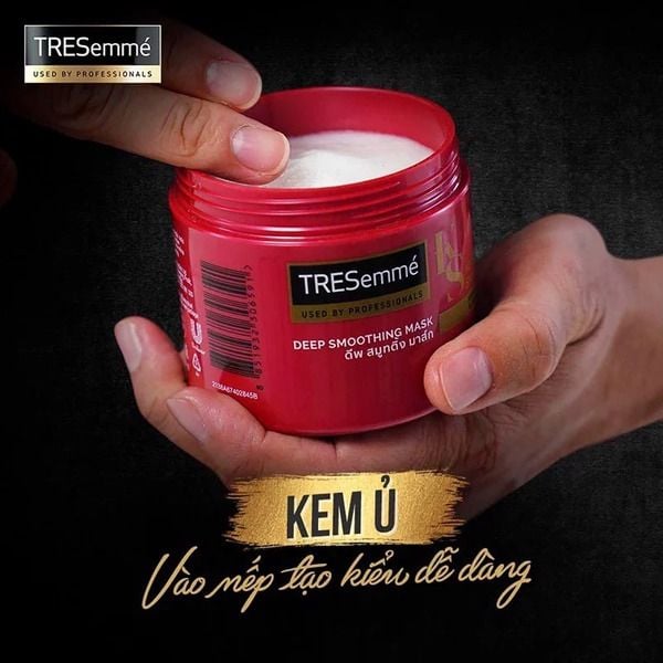 kem_u_cho_toc_vao_nep_tu_thuong_hieu_tresemme_10c5ee84416e4979b117b6ea32dff46b_grande Hũ kem ủ tóc TRESemmé màu đỏ đang được mở, có một người lấy kem từ bên trong.