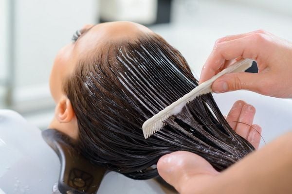 keratin_bao_ve_toc_khoi_tac_nhan_ben_ngoai_2aaa23c9debf4f538d93ba8a98b5711a_grande Người đang gội đầu tại tiệm salon, tóc được chải đều với lược và thoa kem dưỡng.