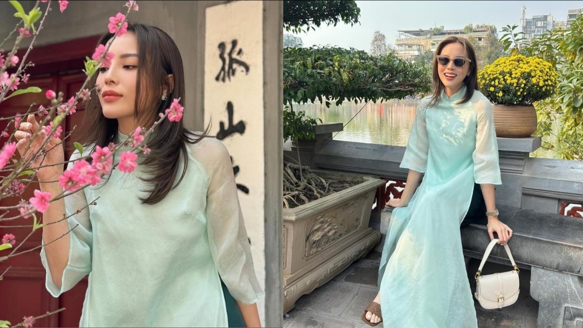 Người phụ nữ mặc áo dài xanh nhạt, đứng cạnh hoa đào và ngồi bên hồ, đeo kính râm, cầm túi xách trắng.