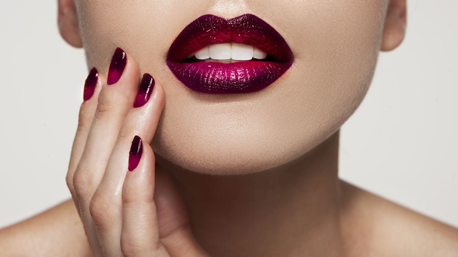 Đôi môi sẫm màu và móng tay đỏ, tạo nên sự phối hợp trang điểm ấn tượng.