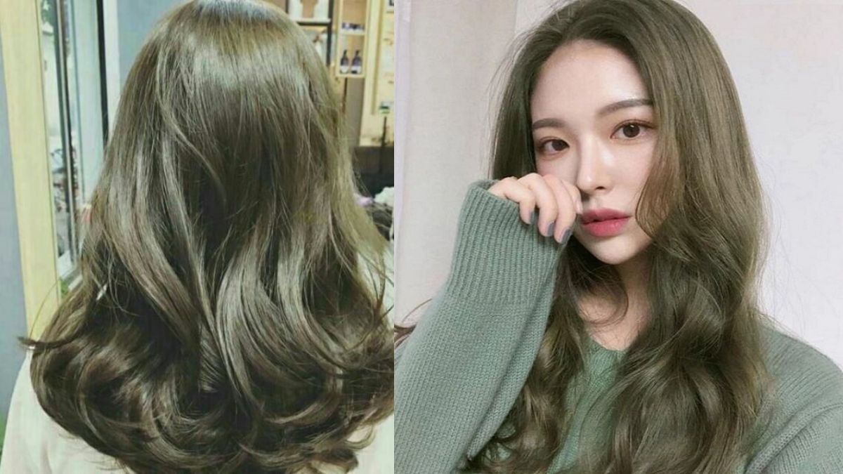 Người phụ nữ với mái tóc dài uốn lượn màu nâu, mặc áo len xanh, tạo dáng chụp ảnh trong nhà.