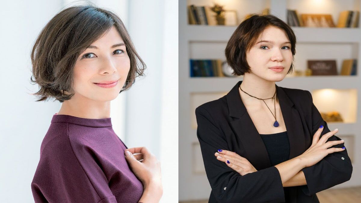 Hai người đứng tạo dáng, một người trong áo tím, một người trong áo đen, nền sách và ánh sáng dịu.