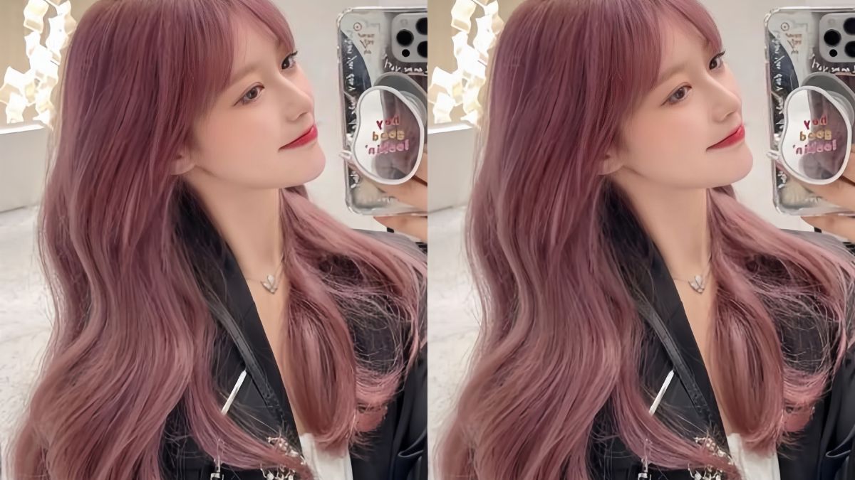 Người với mái tóc dài màu tím, đang chụp ảnh selfie trong gương, mặc áo khoác đen.