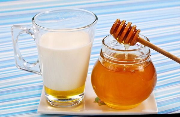 Ly sữa và hũ mật ong trên đĩa trắng, nền sọc xanh trắng.