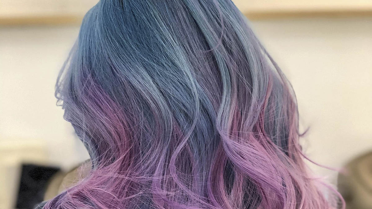 Mái tóc nhuộm màu xanh và tím pastel, tạo thành các lọn sóng mềm mại, nổi bật trên nền sáng.